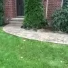 Stamped concrete sidewalk curving into front porch of brick building