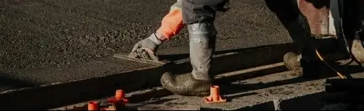 Concrete worker finishing concrete edge with magnesium float