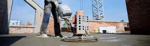 concrete worker using trowel machine to finish rooftop concrete pad
